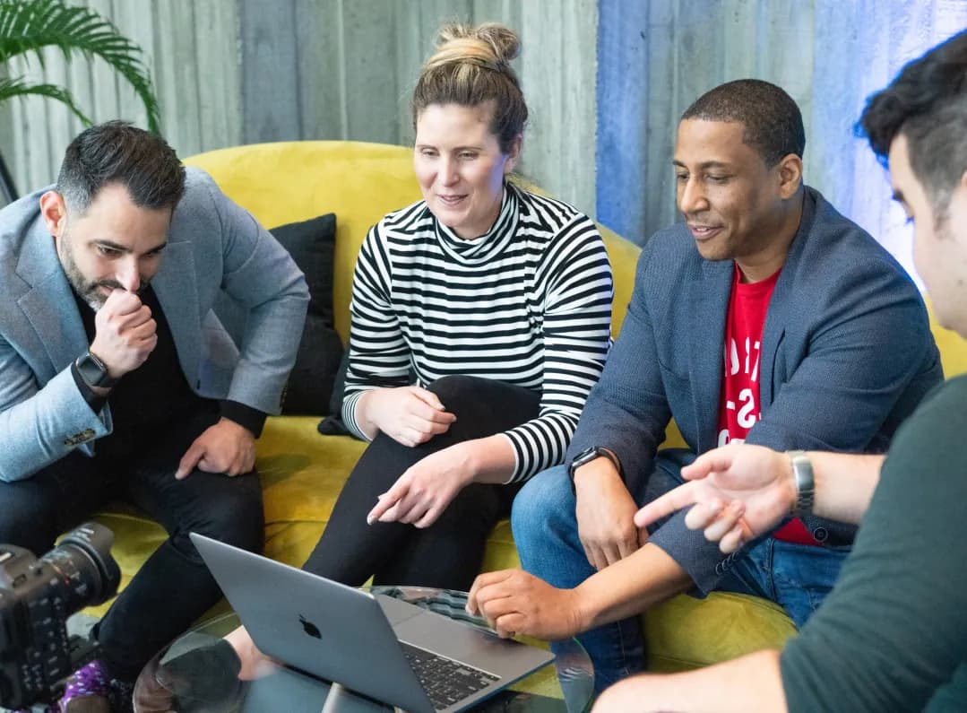 Group smiling while sitting around a computer